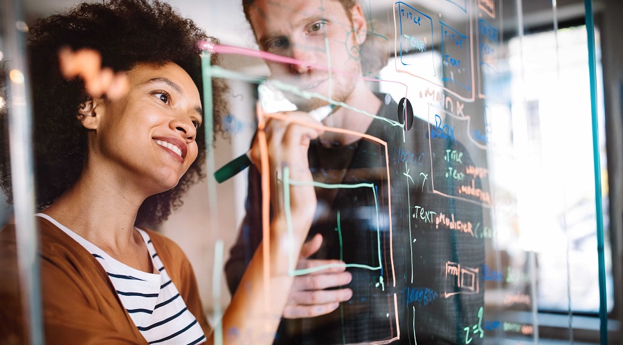 People drawing in a glass board