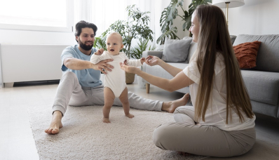 Baby taking its first steps between mother and father